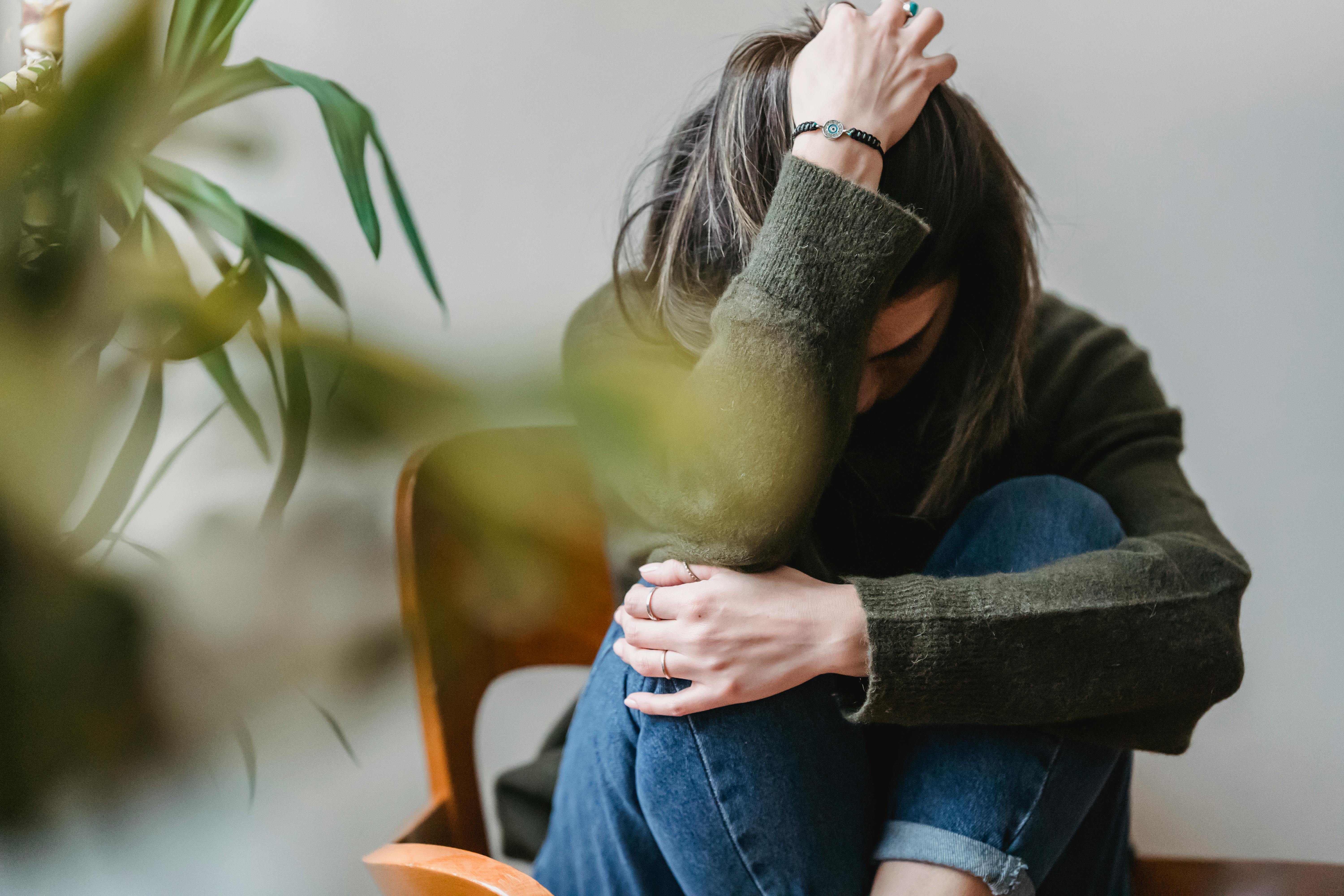 Woman sitting with anxiety, plant beside her