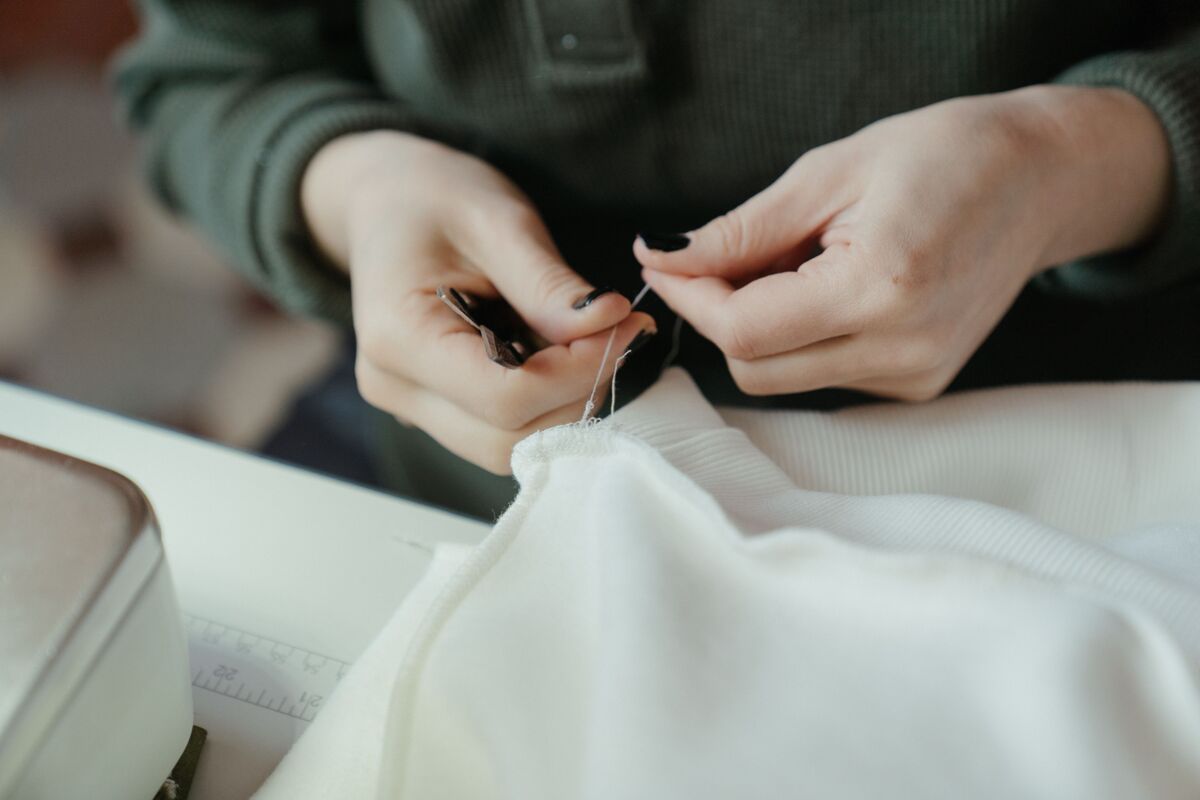 Hands mending a garment — the practice of caring for what you already own