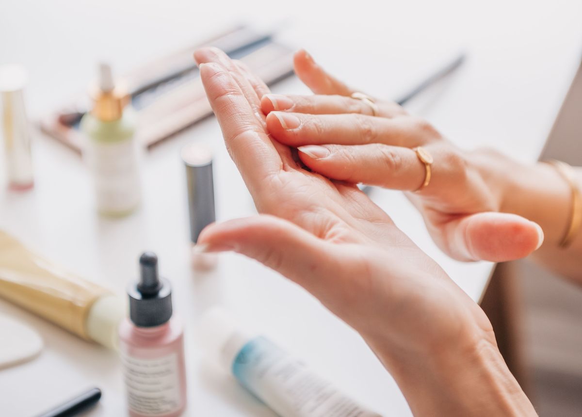 Hands massaging in product at a vanity surrounded by skincare bottles and serums
