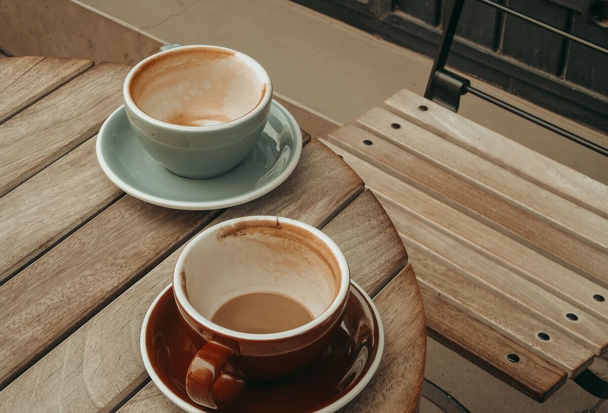 Two empty coffee cups on a cafe table by a window