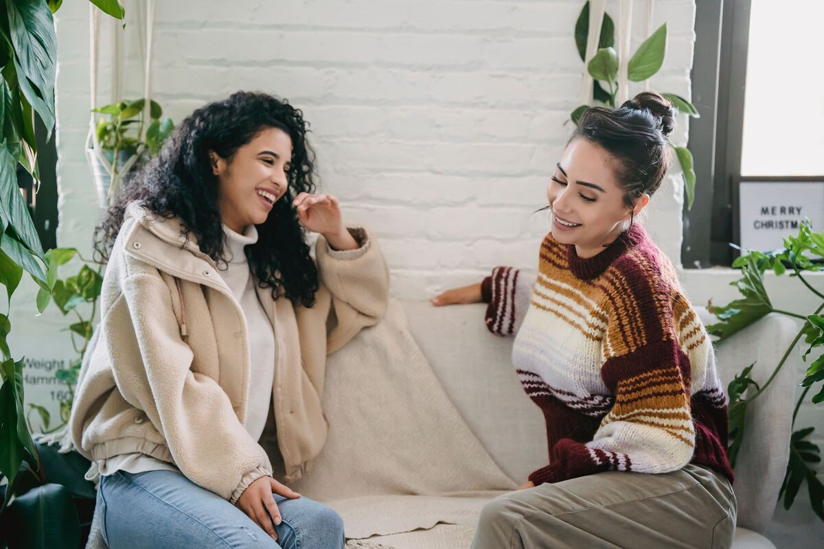 A woman sitting with a friend on a sofa, in easy conversation