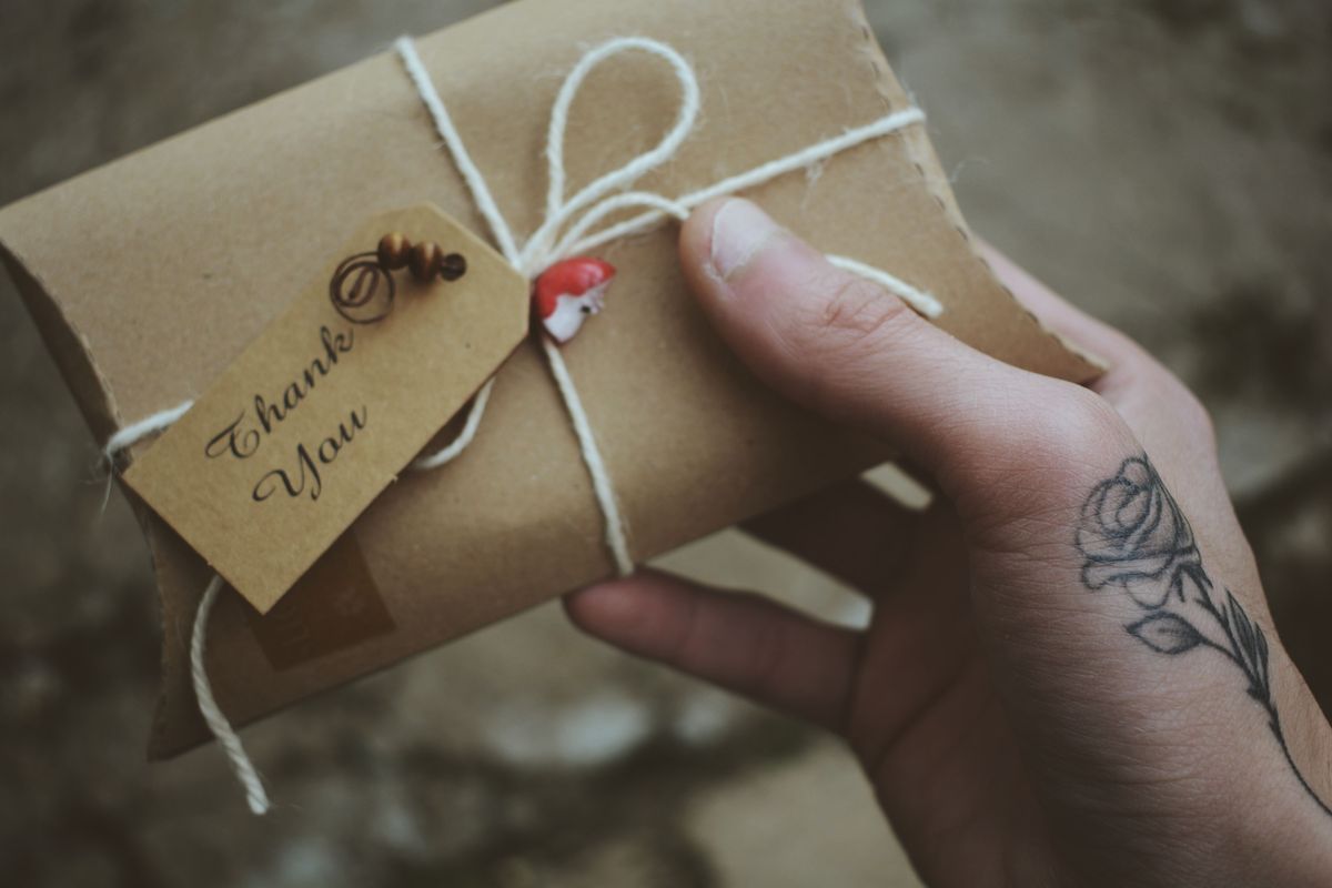 A small wrapped gift tied with string, tagged with a handwritten Thank You note