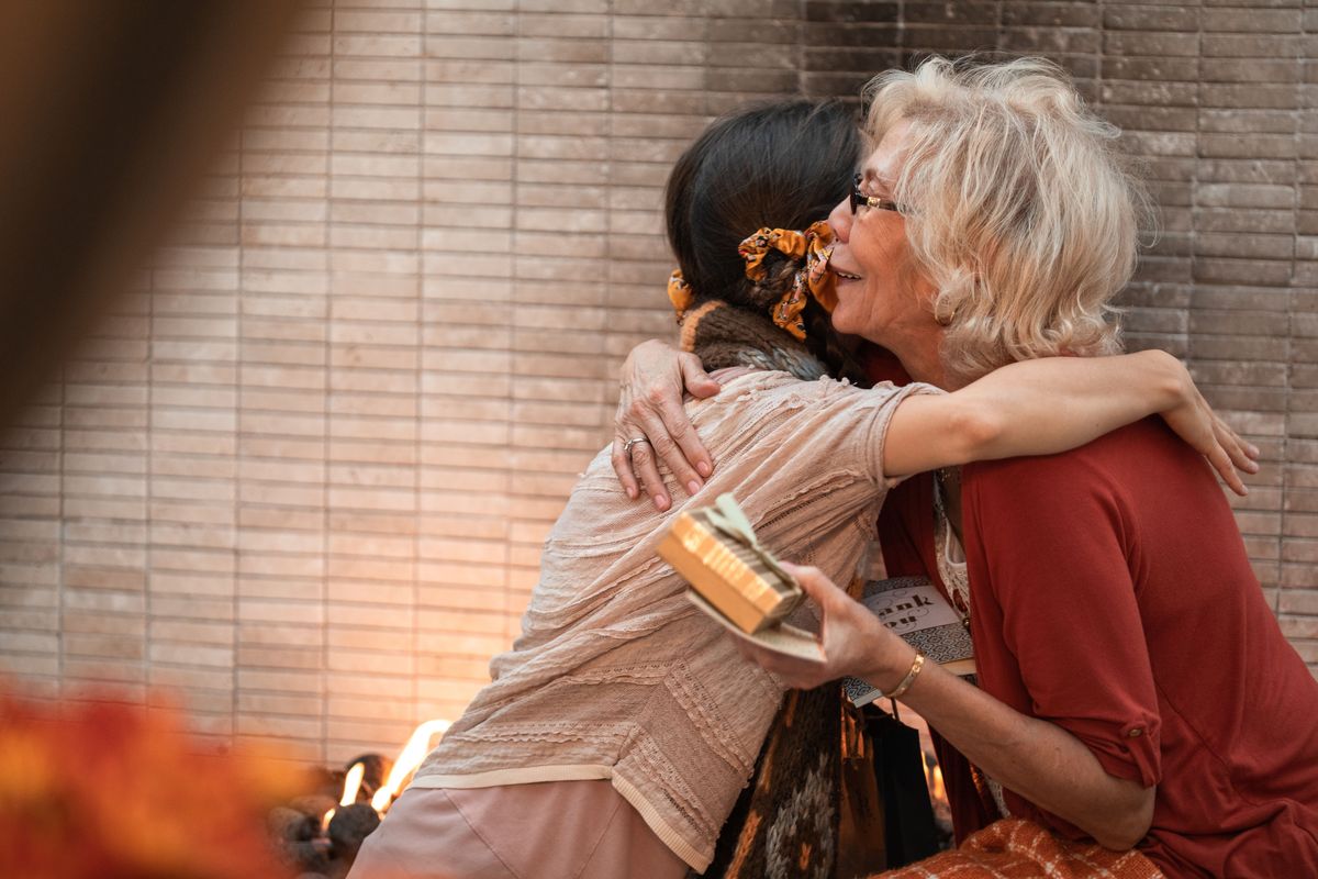 Two women embracing warmly while exchanging a wrapped gift
