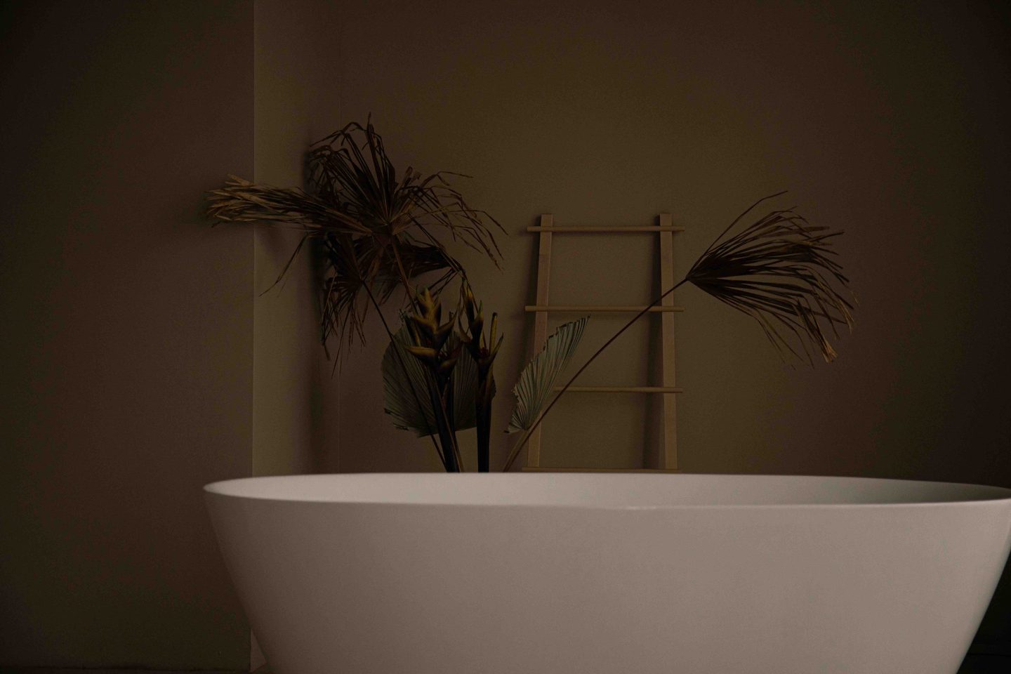 A bedroom with warm eucalyptus color drenching and natural linen