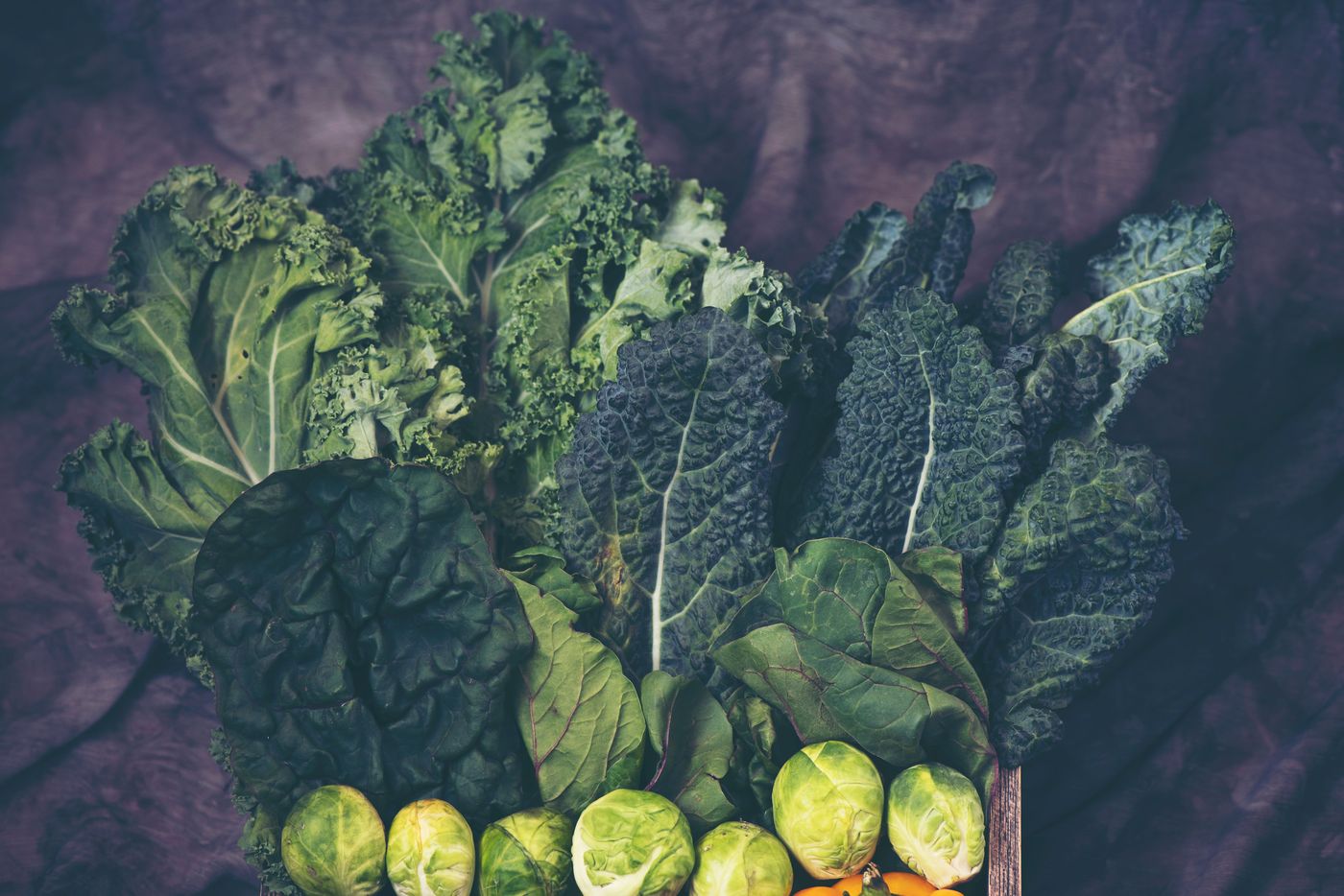 Pumpkin seeds, chia seeds, dark leafy greens and almonds arranged on a table