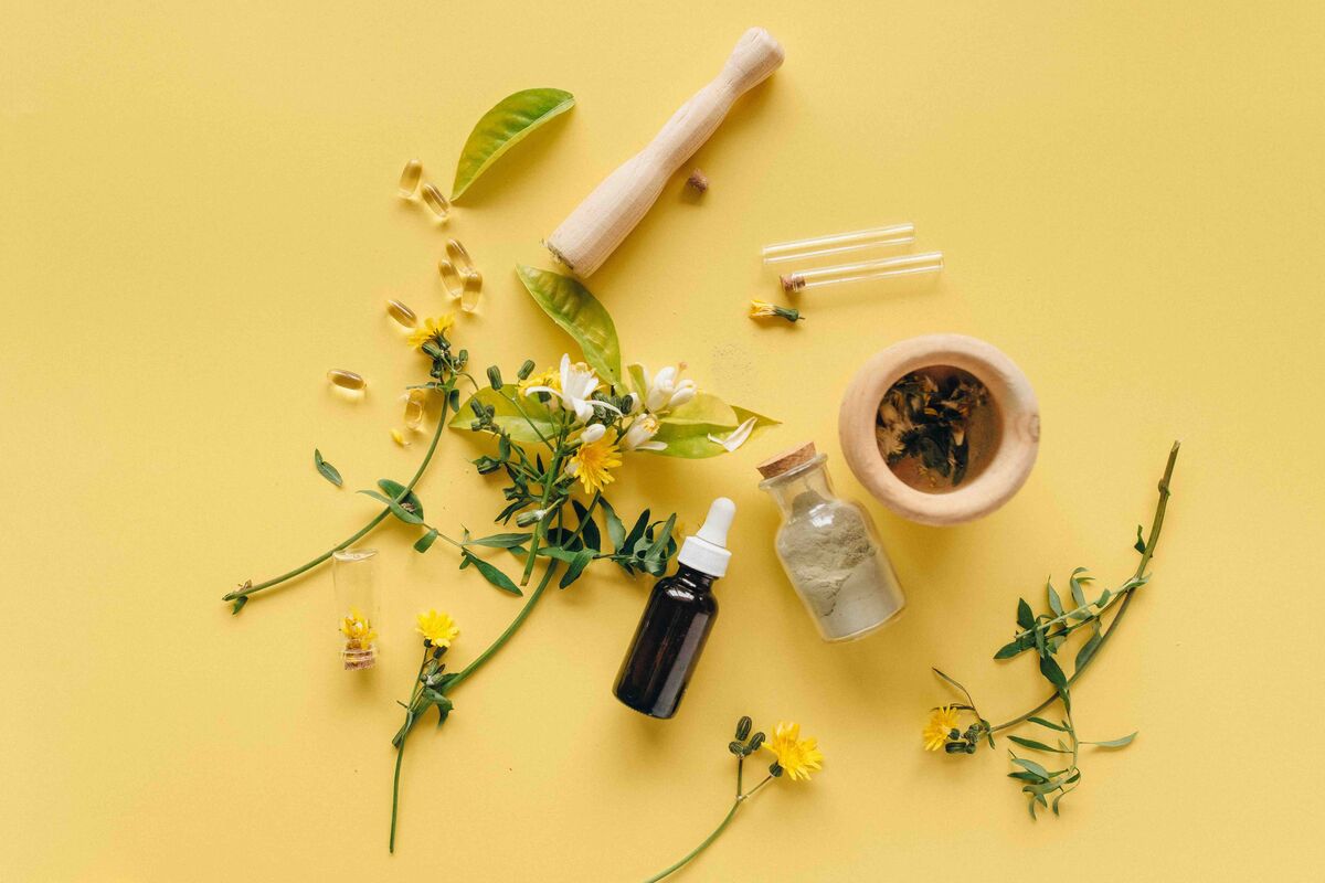 Natural botanical perfume ingredients — dried flowers, essential oil bottles, and raw plant extracts on a marble surface