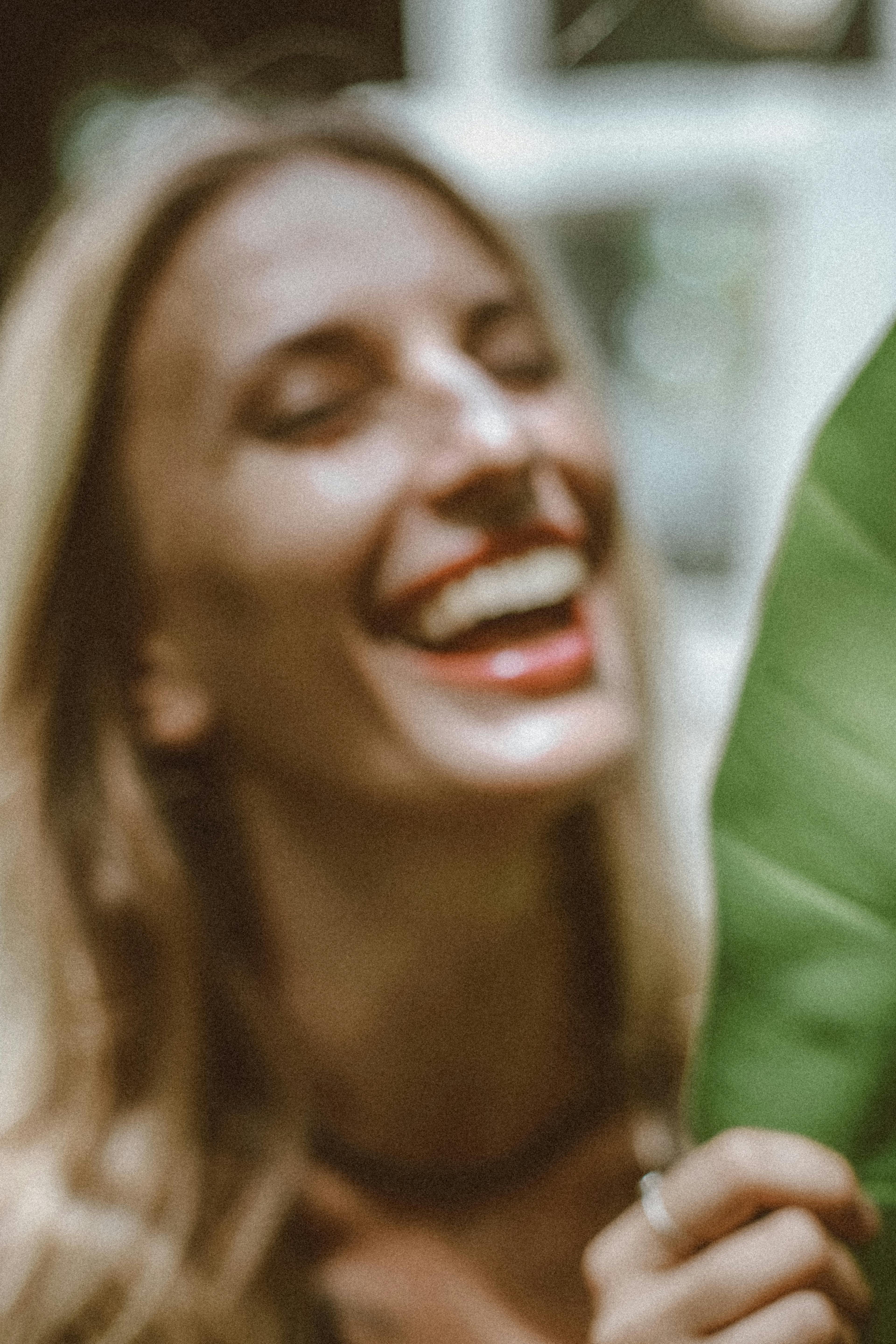 A woman laughing joyfully near a large tropical leaf, glowing skin, warm and natural