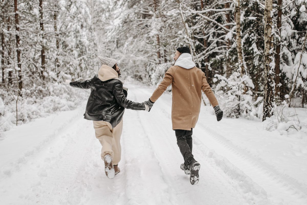 A couple walking close together down a city street, her head resting near his shoulder