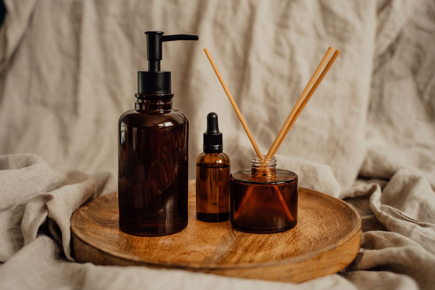 A reed diffuser and candle on a table in soft daylight