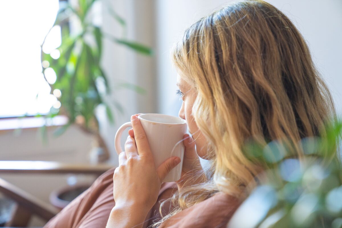 A woman sitting quietly with a cup of tea in soft morning light