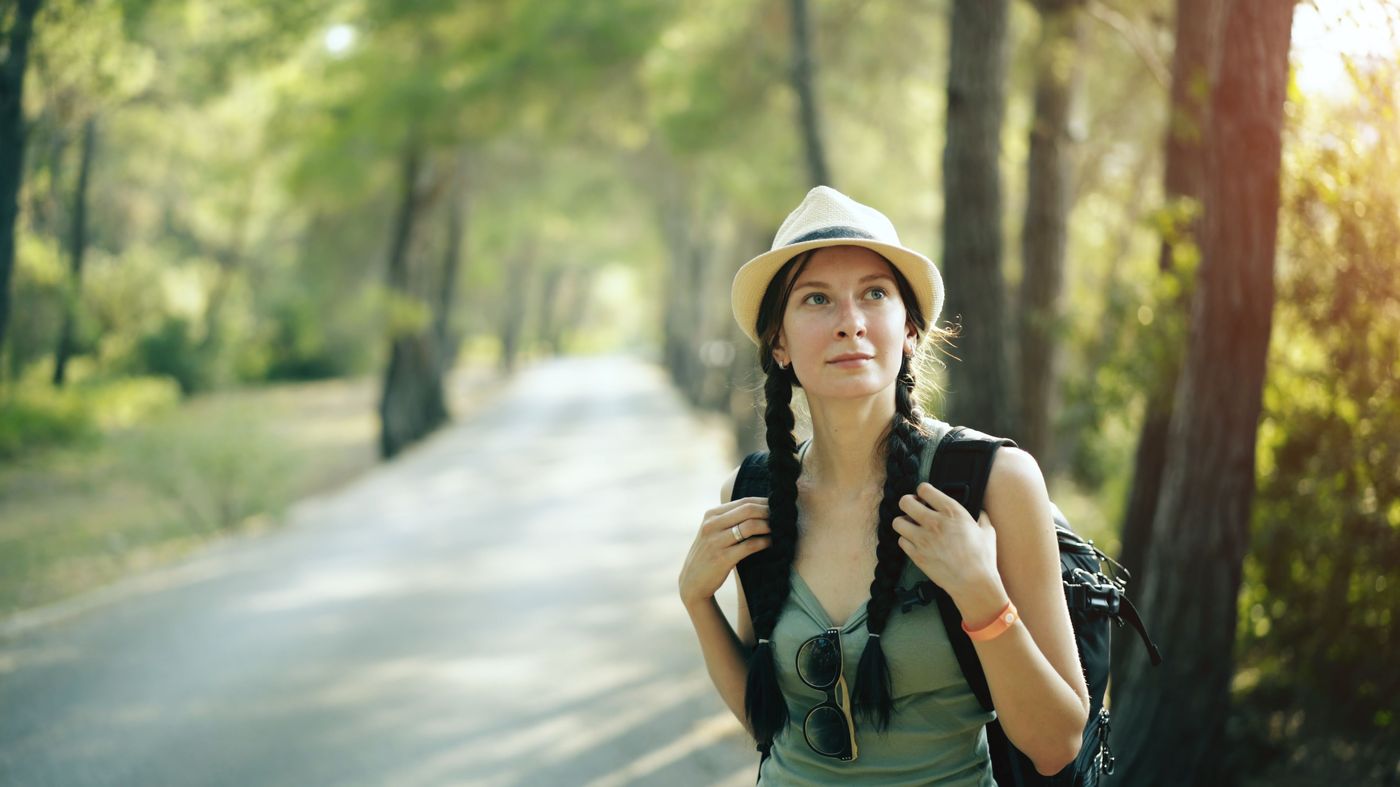 A woman walking alone through a sunlit street in a new city