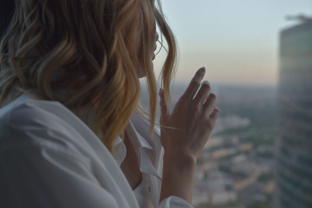 A woman sitting alone by a window, unhurried and at ease in her own company